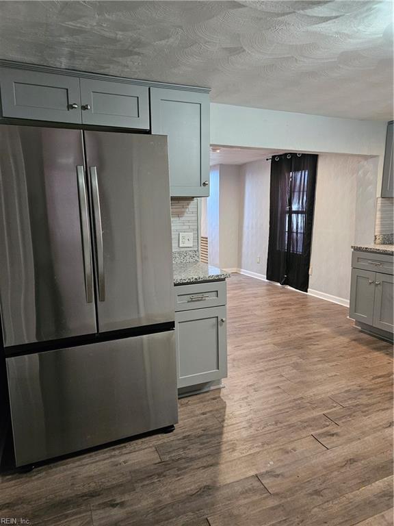 kitchen featuring gray cabinetry, dark wood-type flooring, freestanding refrigerator, and tasteful backsplash