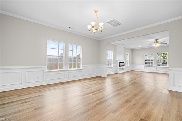 unfurnished living room featuring light wood-style floors, ornamental molding, visible vents, and a wainscoted wall