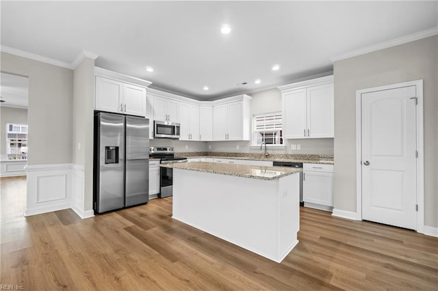 kitchen with a center island, a sink, crown molding, white cabinetry, and stainless steel appliances