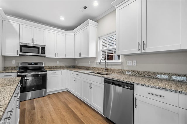 kitchen featuring a sink, white cabinets, light wood-type flooring, and stainless steel appliances