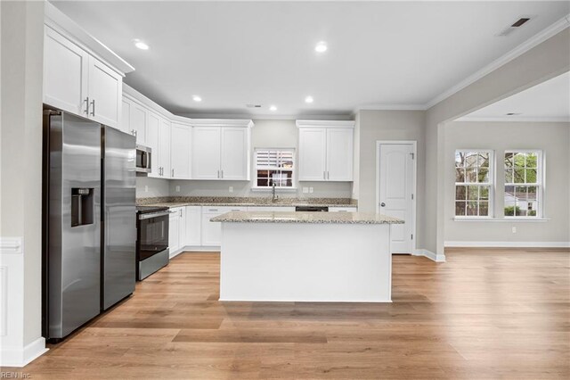 kitchen with ornamental molding, white cabinetry, a kitchen island, visible vents, and stainless steel appliances