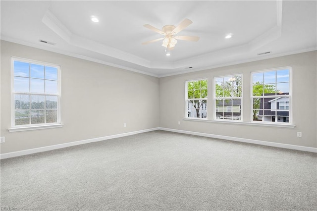 carpeted empty room featuring a wealth of natural light, visible vents, ornamental molding, and a raised ceiling