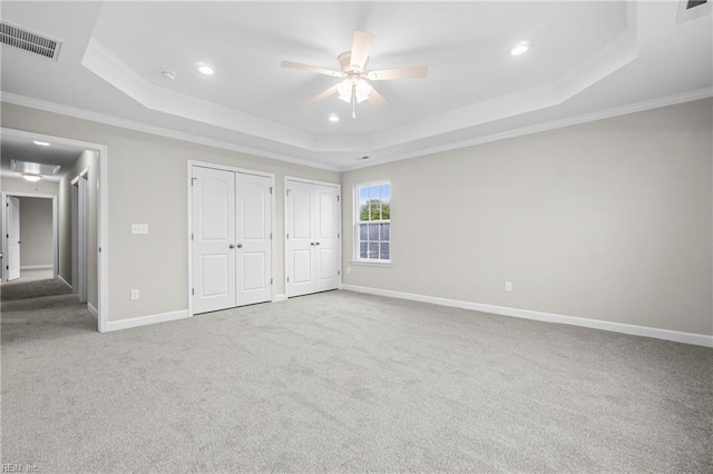 unfurnished bedroom with a tray ceiling, ornamental molding, and visible vents