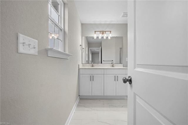bathroom with baseboards, a sink, a chandelier, double vanity, and marble finish floor