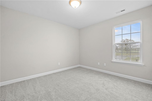 carpeted empty room featuring visible vents, baseboards, and a healthy amount of sunlight