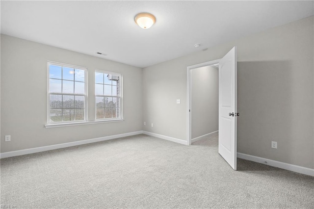 spare room featuring visible vents, baseboards, and light carpet
