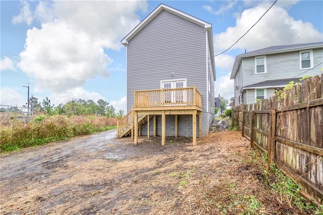 rear view of house with fence, a deck, and stairs