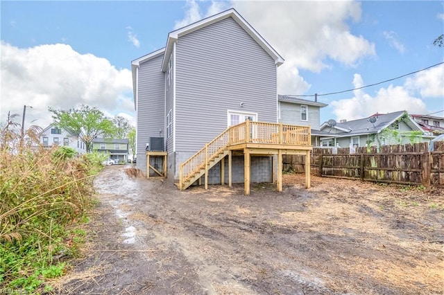 back of property featuring fence, a deck, and stairs