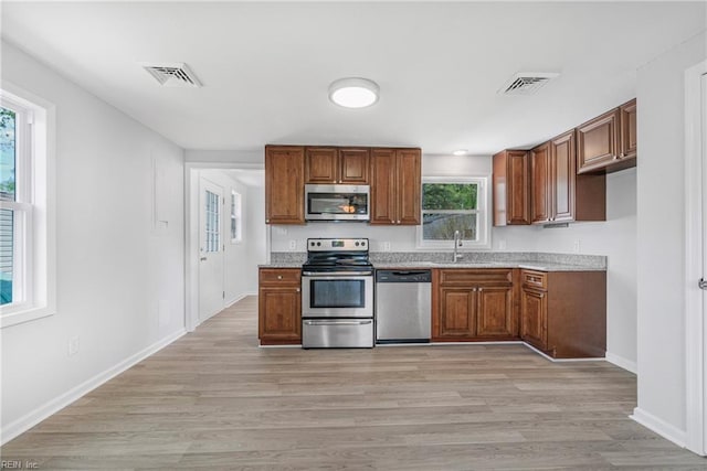 kitchen featuring stainless steel appliances, visible vents, and brown cabinetry