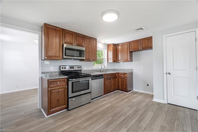 kitchen with brown cabinets, visible vents, light wood finished floors, and stainless steel appliances