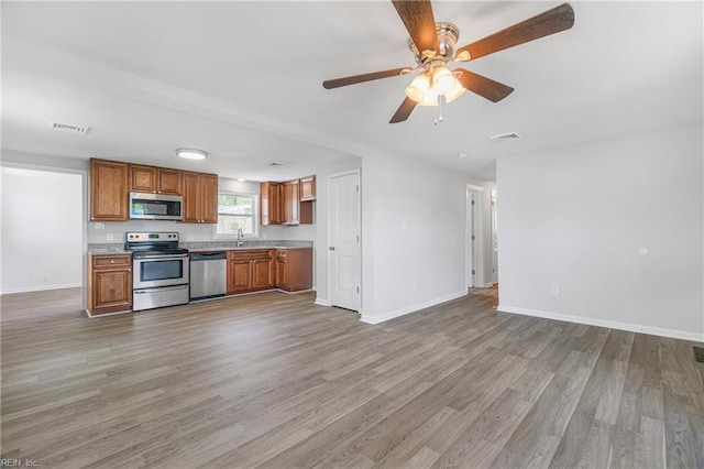 kitchen featuring visible vents, baseboards, appliances with stainless steel finishes, light wood-style floors, and brown cabinets