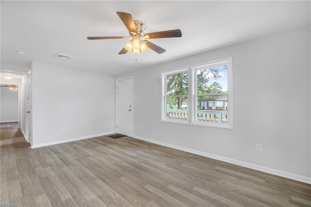 empty room featuring light wood-style floors, visible vents, and ceiling fan