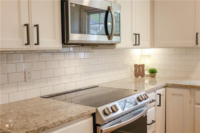 kitchen with white cabinetry, backsplash, appliances with stainless steel finishes, and light stone counters