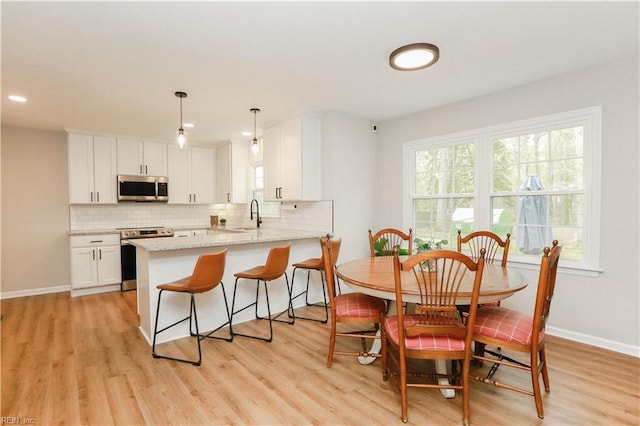 dining room featuring light wood finished floors, baseboards, and recessed lighting