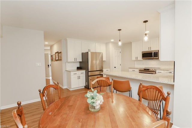 dining area featuring baseboards, light wood-type flooring, and recessed lighting