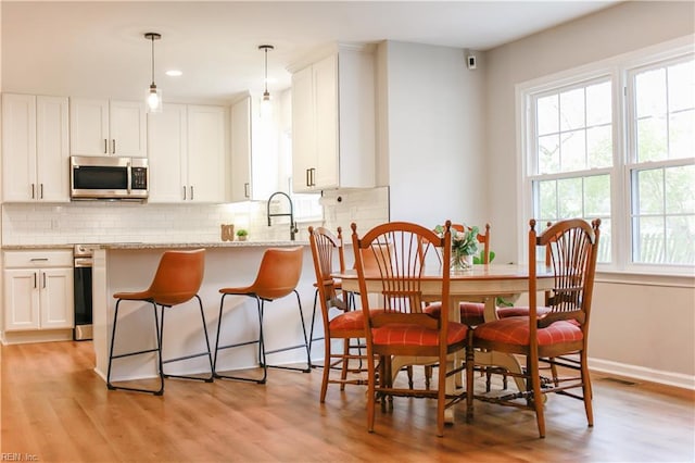dining area with visible vents, a wealth of natural light, and light wood finished floors