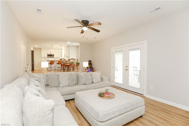 living area featuring light wood-style floors, french doors, a ceiling fan, and visible vents