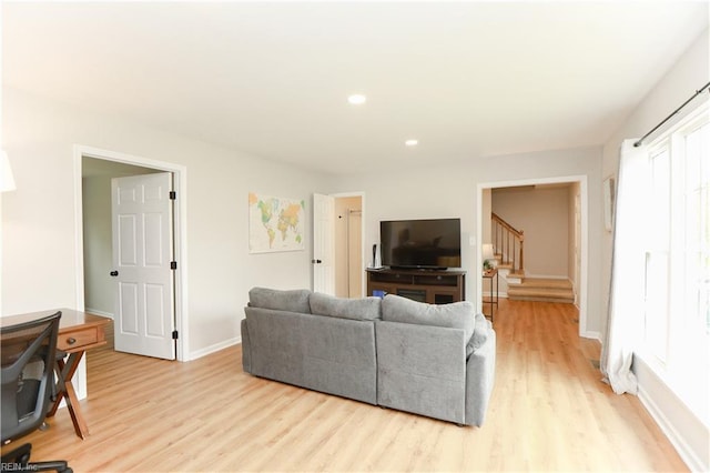 living area featuring recessed lighting, baseboards, stairway, and light wood-style floors