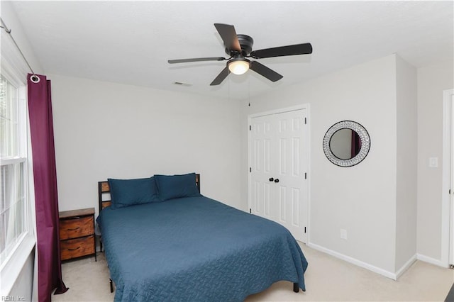 carpeted bedroom featuring a closet, visible vents, baseboards, and a ceiling fan