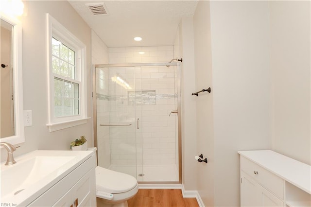 full bathroom featuring a shower stall, vanity, visible vents, toilet, and wood finished floors
