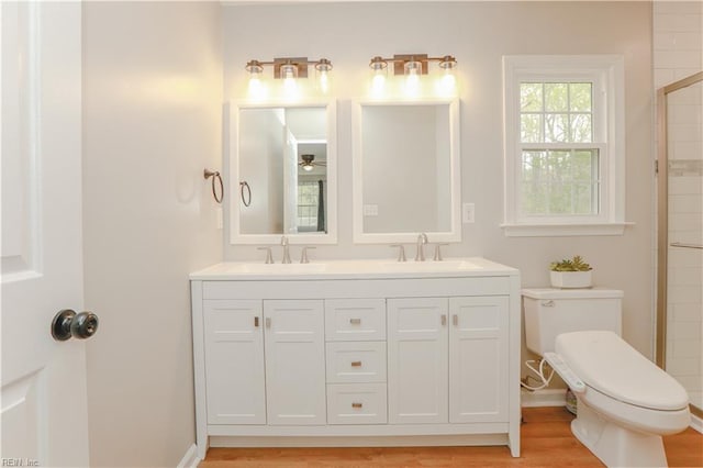 full bathroom featuring toilet, wood finished floors, double vanity, and a sink
