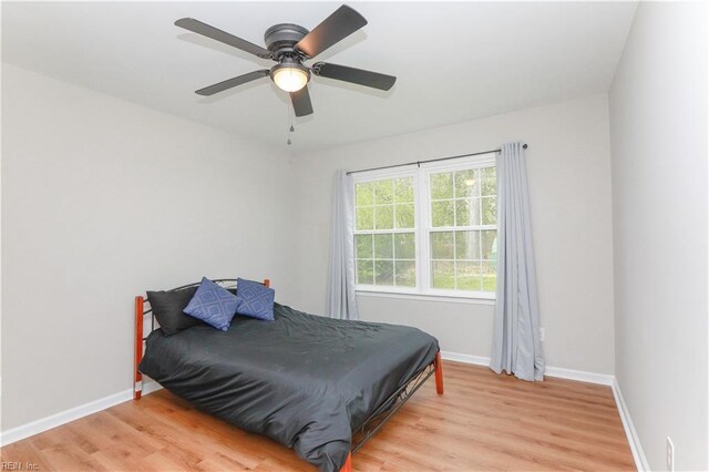 bedroom with baseboards, ceiling fan, and light wood-style floors