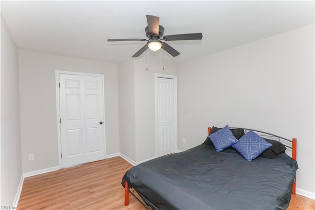 bedroom featuring ceiling fan, a closet, light wood finished floors, and baseboards