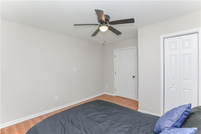 bedroom featuring a closet, ceiling fan, baseboards, and wood finished floors