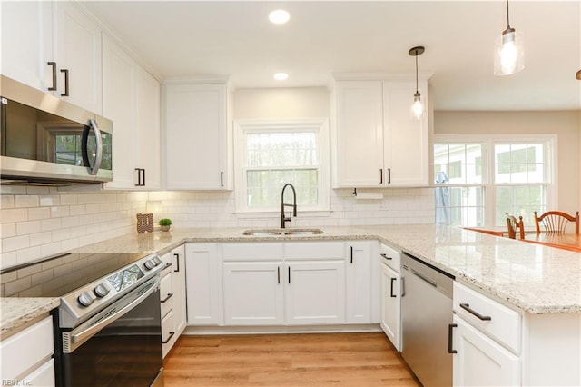kitchen featuring tasteful backsplash, a peninsula, white cabinetry, appliances with stainless steel finishes, and a sink