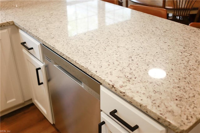 interior details featuring white cabinets, light stone counters, dishwasher, and dark wood finished floors