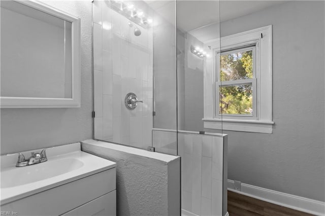 bathroom with a tile shower, wood finished floors, and vanity