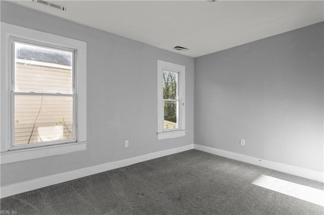 unfurnished room featuring visible vents, baseboards, and dark carpet