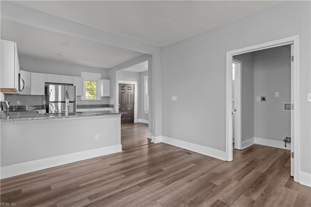 kitchen with white cabinetry, appliances with stainless steel finishes, a peninsula, and dark wood-type flooring