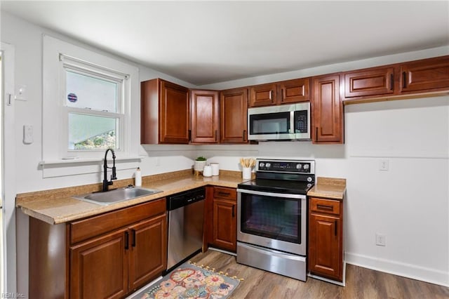 139 Ash Ave, Newport News, VA 23607 - kitchen with light countertops, brown cabinetry, appliances with stainless steel finishes, a sink, and wood finished floors