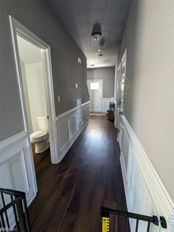 731 33rd St, Newport News, VA 23607 - corridor featuring wainscoting, a decorative wall, dark wood finished floors, and a textured ceiling