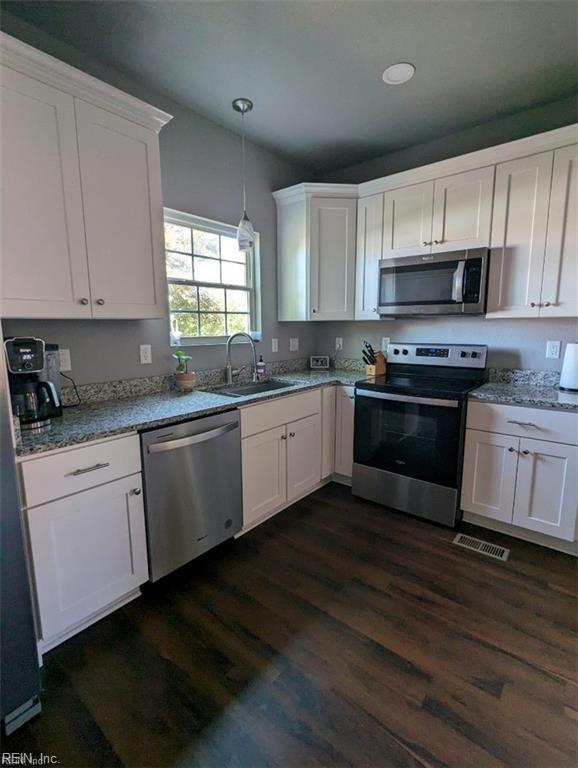731 33rd St, Newport News, VA 23607 - kitchen with white cabinets, a sink, hanging light fixtures, stainless steel appliances, and dark wood-style floors