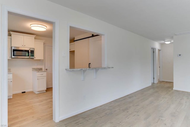1793 Old Buckroe Rd, Hampton, VA 23664 - unfurnished living room featuring a barn door, light wood-style floors, and baseboards