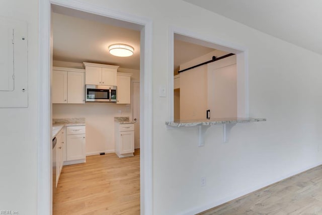 1793 Old Buckroe Rd, Hampton, VA 23664 - kitchen featuring light wood-style floors, stainless steel microwave, white cabinetry, and a barn door