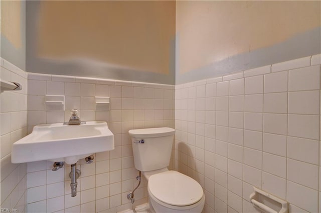 half bathroom featuring a sink, tile walls, and toilet