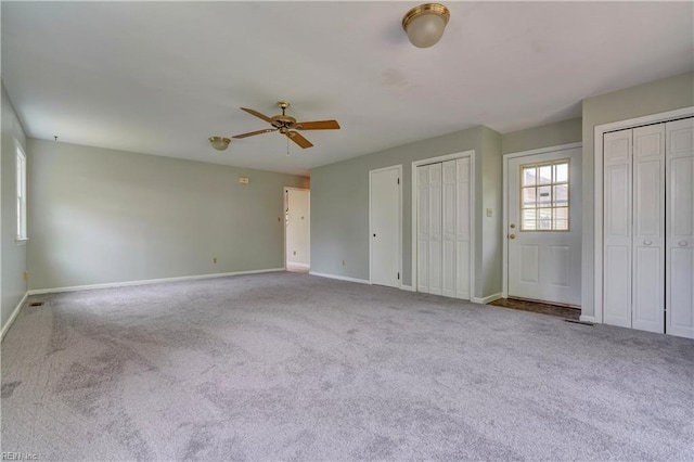 unfurnished bedroom with baseboards, two closets, and carpet floors