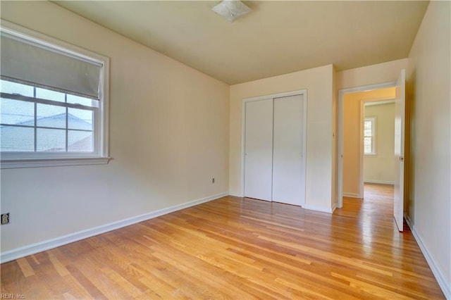 unfurnished bedroom featuring light wood-style floors, a closet, and baseboards