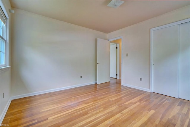 unfurnished bedroom featuring a closet, baseboards, and light wood-type flooring
