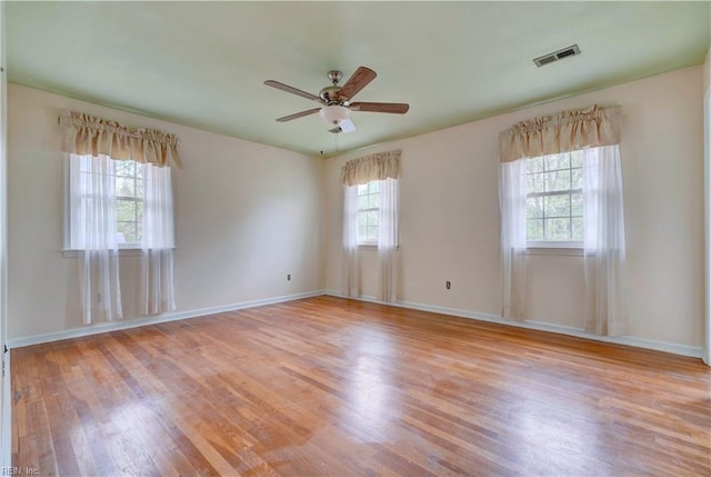 empty room featuring visible vents, light wood-style flooring, a ceiling fan, and baseboards
