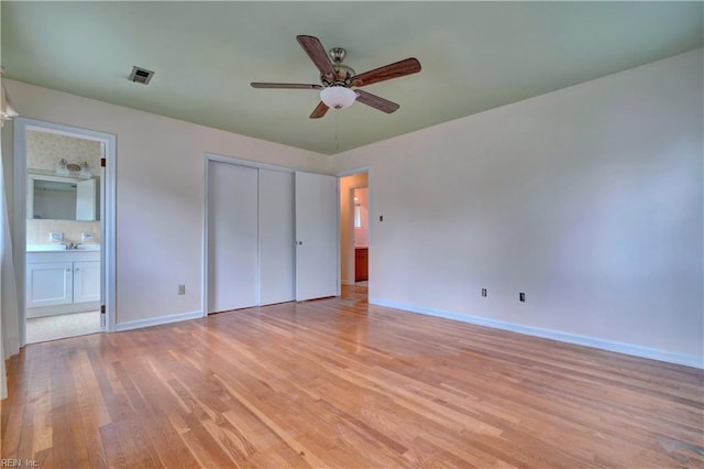 unfurnished bedroom with connected bathroom, light wood-style flooring, a closet, visible vents, and baseboards