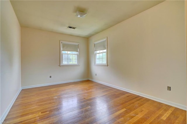 unfurnished room featuring light wood finished floors, visible vents, and baseboards