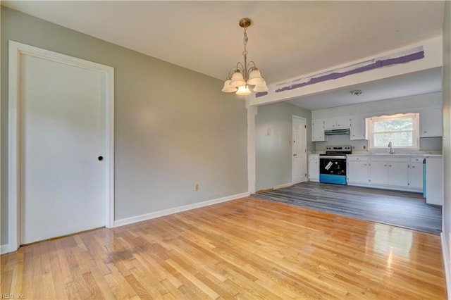 interior space with a sink, baseboards, an inviting chandelier, and light wood-style floors