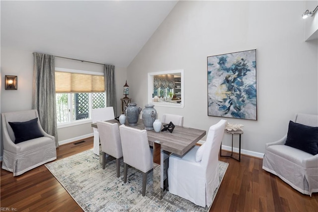 dining space with wood finished floors, high vaulted ceiling, baseboards, and visible vents