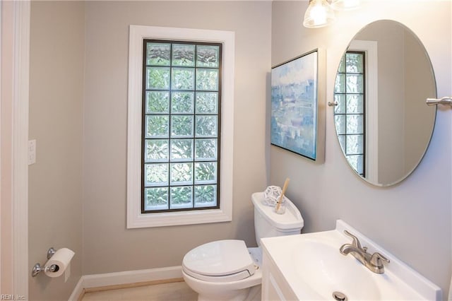 half bathroom with toilet, a sink, and baseboards