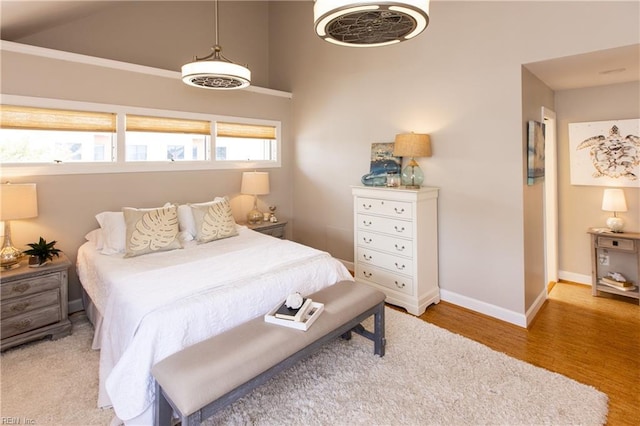 bedroom featuring baseboards, vaulted ceiling, and wood finished floors