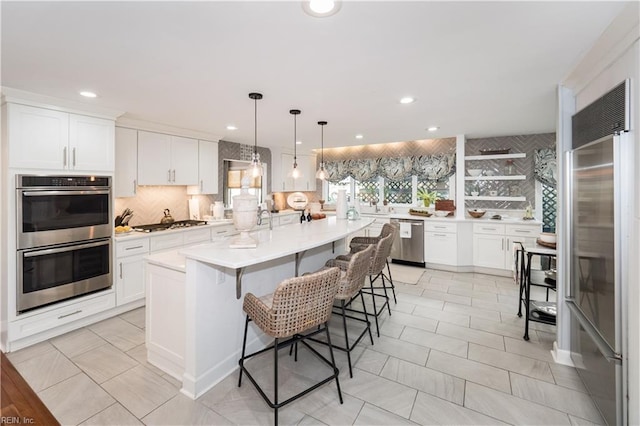 kitchen featuring a center island, light countertops, white cabinetry, stainless steel appliances, and decorative backsplash